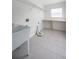 Bright laundry room with utility sink, shelving, and tile floor at 3602 Juneberry Dr, Wesley Chapel, FL 33543