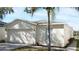 Beige single-story home featuring an attached two-car garage, neutral landscaping, and a sidewalk at 7833 Carriage Pointe Dr, Gibsonton, FL 33534
