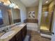 Bathroom with double sinks, granite countertops, a soaking tub, and a glass-enclosed shower at 8451 Karpeal Dr, Sarasota, FL 34238