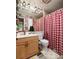 Bathroom with red and white checkered shower curtain and light wood vanity at 10200 Gandy N Blvd # 1313, St Petersburg, FL 33702