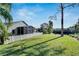 Fenced backyard with a screened-in patio, lush green lawn, and a tall tree at 10707 Banfield Dr, Riverview, FL 33579