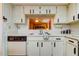 Well-lit kitchen featuring a view to living area, a double sink and white cabinetry at 3055 Casa Del Sol Cir # 303, Clearwater, FL 33761