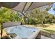 Modern hot tub with shade cover and lush green backyard view at 1242 Holiday Dr, Tarpon Springs, FL 34689