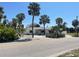 Inviting single-story home featuring tropical landscaping with mature palms and a well-manicured lawn at 909 Mandalay Ave, Clearwater Beach, FL 33767
