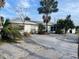 Front view of a white single story home with a gravel driveway at 909 Mandalay Ave, Clearwater Beach, FL 33767