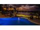 Stunning pool area at twilight with vibrant uplighting, lounge seating, and waterfront views at 118 Harbor View Ln, Belleair Bluffs, FL 33770
