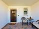 Covered entryway with seating area and dark brown front door at 16847 Whisper Elm St, Wimauma, FL 33598