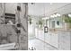 Modern main bathroom with dual sinks, white cabinetry, marble floors, and large glass shower at 5004 W Leona St, Tampa, FL 33629