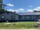 Gray house with a black roof, fresh landscaping, and a red door at 10811 Williams Rd, Thonotosassa, FL 33592