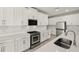 Modern kitchen featuring white cabinetry, stainless steel appliances, quartz countertops, and a herringbone tile backsplash at 11971 Starbright Path, Venice, FL 34293