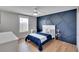 Cozy bedroom with blue accent wall and hardwood floors at 12783 Maple Bonsai Dr, Riverview, FL 33579