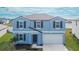Two-story house with blue exterior, white garage door, and landscaping at 12783 Maple Bonsai Dr, Riverview, FL 33579