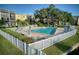 Community pool area with white picket fence, lounge chairs, and umbrellas, framed by trees at 14130 Rosemary Ln # 4311, Largo, FL 33774