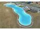 Aerial view of crystal-clear lagoon pool and surrounding landscape at 17523 Holly Well Ave, Wimauma, FL 33598
