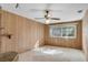 View of the living room highlighting the wood paneling, ceiling fan, and window at 4403 Northrop Ter, Tampa, FL 33618