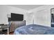 Bedroom with a dark blue bedspread, wood floor, gray dresser, large TV, and desk at 4600 16Th N St, St Petersburg, FL 33703