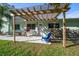 Inviting home exterior featuring a pergola, landscaping, and a blue chair at 8390 64Th N St, Pinellas Park, FL 33781