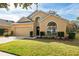 Tan house with a two-car garage and nicely landscaped front yard at 11948 Palm Bay Ct, New Port Richey, FL 34654