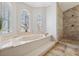 Bright bathroom with an oval soaking tub, large windows and an elegant tiled shower at 224 7Th E St, Tierra Verde, FL 33715