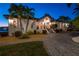 Exterior elevation showcases lush landscaping, exterior lighting, a paver driveway, and mature palm trees at 224 7Th E St, Tierra Verde, FL 33715
