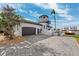 Exterior view features a tower, brick paver driveway, lush landscaping, and an attached two car garage at 224 7Th E St, Tierra Verde, FL 33715