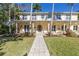 Inviting front yard of a yellow two-story home with a paved walkway leading to the entrance at 323 Coffee Pot Ne Dr, St Petersburg, FL 33704
