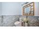 Small bathroom with glass sink, stone tile, and a frame mirror at 514 Ryans Woods Ln, Palm Harbor, FL 34683