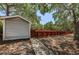 Grey storage shed with adjacent red fence and walkway at 514 Ryans Woods Ln, Palm Harbor, FL 34683