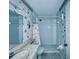 Bathroom with tiled shower, marble countertop, and seashell-themed wallpaper at 8198 Terrace Garden N Dr # 407, St Petersburg, FL 33709