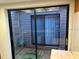 Enclosed patio area featuring sliding glass doors, wood decking, and views of exterior shrubbery at 10 Woodridge Cir, Oldsmar, FL 34677