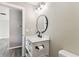 Bathroom features a white vanity with dark hardware, oval mirror and modern lighting at 102 Shore E Dr, Oldsmar, FL 34677