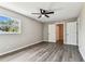 Bright bedroom features a window, ceiling fan, wood-look floors, and an entrance to another room at 102 Shore E Dr, Oldsmar, FL 34677
