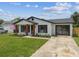 Charming single-story home featuring a well-manicured lawn, driveway, and black trim at 102 Shore E Dr, Oldsmar, FL 34677