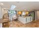 Bright kitchen with island, skylight, terracotta tile flooring, and unique wicker swingasan chairs at 9830 Mark Twain Ln, Port Richey, FL 34668