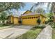 A yellow house with a two-car garage and lush landscaping at 3022 Beaver Pond Trl, Valrico, FL 33596