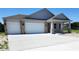 Charming exterior featuring a three-car garage, light gray stucco, brick accents, and concrete driveway at 413 Shannon Estates Ct, Plant City, FL 33563