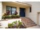 Front entrance with brick steps, blue door, and lush tropical landscaping at 107 17Th St, Belleair Beach, FL 33786