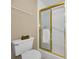 Bathroom features a toilet and a shower with a gold-trimmed door and a towel hanging inside at 100 Bluff View Dr # 207C, Belleair Bluffs, FL 33770