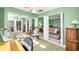 View of a bedroom with light green walls and connected rooms with sitting chairs and a rocking chair at 100 Bluff View Dr # 207C, Belleair Bluffs, FL 33770
