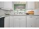 Well-lit kitchen featuring white cabinets, tile backsplash, and a pass-through to the dining room at 100 Bluff View Dr # 207C, Belleair Bluffs, FL 33770