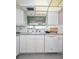 Well-lit kitchen featuring white cabinets, tile backsplash, and a pass-through to the dining room at 100 Bluff View Dr # 207C, Belleair Bluffs, FL 33770