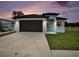 Light blue home with dark trim and attached garage at dusk at 1510 W Rambla St, Tampa, FL 33612