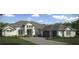 Elegant two-story home with a gray tiled roof, arched entryway, and three-car garage at 5111 Lake Toscana Dr, Wimauma, FL 33598