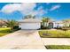 White house with a tile roof, landscaping, and a two-car garage at 728 Thistlelake Dr, Venice, FL 34293