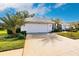 White house with a tile roof, landscaping, and a two-car garage at 728 Thistlelake Dr, Venice, FL 34293
