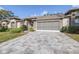 Tan two-story house with paver driveway and landscaping at 8041 Green Pines Ter, Spring Hill, FL 34606