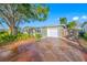 Front view of a single story house with a large tree, attached garage, and a long driveway at 8573 109Th Way, Seminole, FL 33772