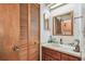 Compact bathroom with a vanity sink, mirror, and louvered closet doors at 11511 113Th St # 27C, Largo, FL 33778