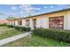 Exterior elevation of a condo building with neatly trimmed bushes, a concrete pathway, and decorative elements, set against a cloudy sky at 11511 113Th St # 27C, Largo, FL 33778
