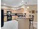 Modern kitchen with light wood cabinets, black appliances, and granite countertops at 225 Mystic Falls Dr, Apollo Beach, FL 33572